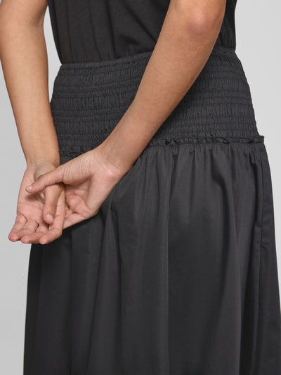 Frauenmodel trägt Midirock mit Smok-Detail von Comma, schwarzer Baumwoll-Mix, elastischer Bund, A-Linie, Detailaufnahme Rückansicht.