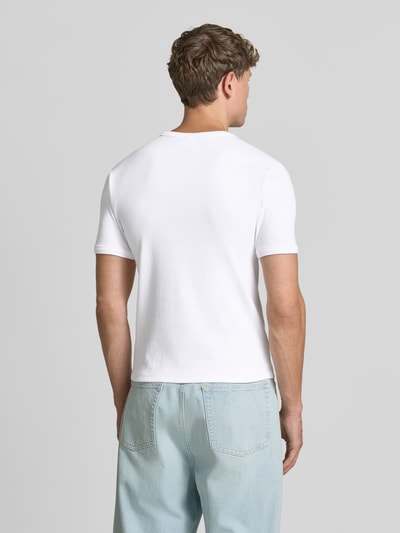 Męski model nosi T-Shirt in Ripp-Optik mit Rundhalsausschnitt od Jake*s, mieszanka bawełny i elastanu, krój slim fit, efekt prążkowania, okrągły dekolt, długość tyłu w rozmiarze M: 56 cm, biała gładka tkanina, całkowity widok z tyłu.