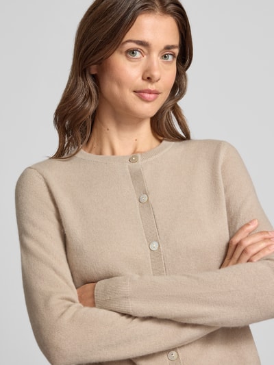 Vrouwenmodel draagt gebreid jack uit puur kasjmier met knoopsluiting, regular fit, ribboorden, beige tinten, Christian Berg Woman, close-up bovenlichaam.
