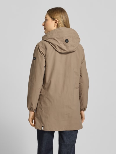 Frauenmodel trägt parka o prostym kroju z kapturem na troki, naszywki z logo, kieszenie z patką, model 'AMETI' od khujo, długość tyłu w rozmiarze S: 81 cm, szerokość ramion w rozmiarze S: 46 cm, szerokość w rozmiarze S: 50 cm, długość rękawów w rozmiarze S: 55 cm, beżowy kolor, matowa tekstura, całkowity widok z tyłu