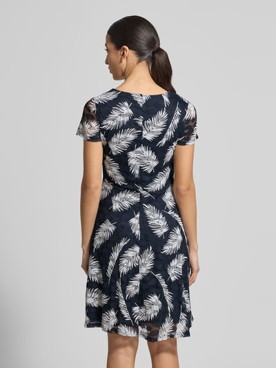 Vrouwenmodel draagt Knielanges Kleid mit Rundhalsausschnitt van Apricot in zwart-wit bladpatroon, getailleerde fit, knielengte, stretchmateriaal, ruglengte maat S 96 cm, borstbreedte 39 cm, mouwlengte 15 cm, detail van gerimpelde stof, volledige achterkant weergave.