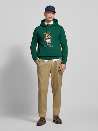 Männermodel trägt Regular Fit Hoodie aus Baumwoll-Mix von Polo Ralph Lauren, Optik: Unifarben, Motiv-Print, Ganzkörperansicht von vorne.