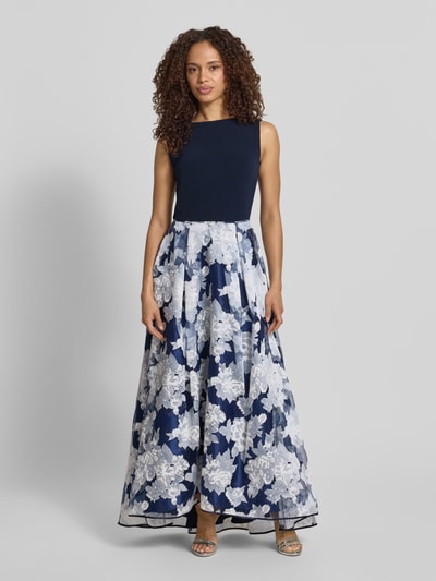 Frauenmodel trägt Abendkleid mit rückseitigem V-Ausschnitt von Christian Berg Cocktail, in Dunkelblau und Weiß mit Blumenmuster, Material-Mix mit Stretch-Anteil, Taillierter Schnitt, Maxikleid, U-Boot-Ausschnitt, Rückseitiger V-Ausschnitt und Rückenreißverschluss, Rückenlänge Größe 36: 130 cm, Brustweite 47 cm, Ganzkörperansicht von vorne.