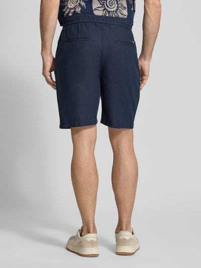 Männermodel trägt Shorts aus Baumwoll-Leinen-Mix Modell 'FAVE' von Scotch & Soda, dunkelblau, Regular Fit, elastischer Bund, Ganzkörperansicht Rückansicht. Bundweite 42 cm, Innenbeinlänge 21 cm bei Größe 32.