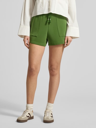 Frauenmodel trägt grüne Sweatshorts mit Seitentaschen von Scotch & Soda, elastischer Material-Mix, gerader Schnitt, Nahaufnahme Oberschenkel.