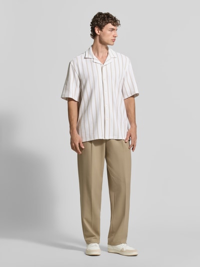 Männermodel trägt Relaxed Fit Kurzarmhemd aus Baumwoll-Mix von BOSS mit Allover-Muster, Reverskragen, beige-weiße Töne, Ganzkörperansicht von vorne.