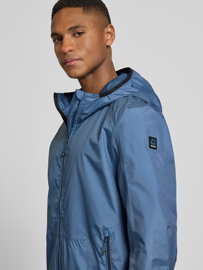 Mannelijk model draagt Jacke mit Kapuze Modell 'KOS' van Killtec in blauw met kap, rechte fit, label-patch, detailopname bovenlichaam.
