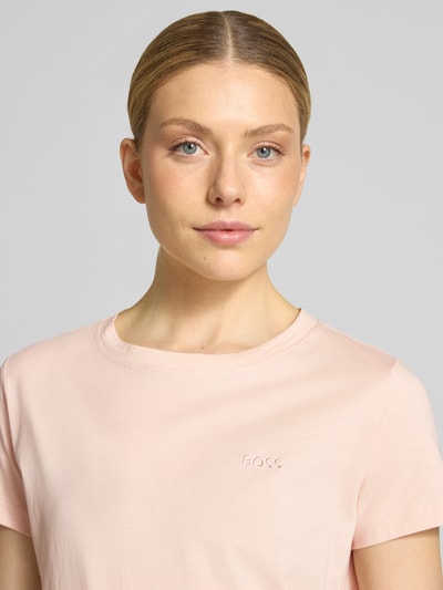 Frauenmodel trägt Regular Fit T-Shirt aus reiner Baumwolle Modell 'ESOGO' von BOSS Orange in zartem Rosa, unifarben, Label-Schriftzug, Nahaufnahme Oberkörper.