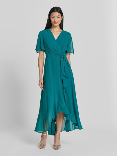 Modelka kobieca ma na sobie 'Cocktailkleid in Wickel-Optik' od Christian Berg Cocktail, turkusowy szyfon, krój taliowany, pasek, długość midi, szerokość w rozmiarze 36: 40 cm, długość tyłu w rozmiarze 36: 35 cm, długość rękawa w rozmiarze 36: 29 cm, widok całej sylwetki z przodu.