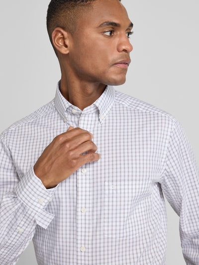 Männermodel draagt Regular Fit Businesshemd met button-down-kraag van OLYMP, wit met fijn ruitpatroon, borstzak en logostiksel, katoen. Nahaufnahme Oberkörper.