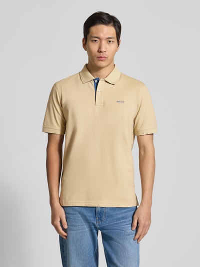 Männermodel trägt Regular Fit Poloshirt mit Logo-Stitching von Gant, beiger Baumwoll-Mix, Polokragen, Kurzarm, Ganzkörperansicht von vorne