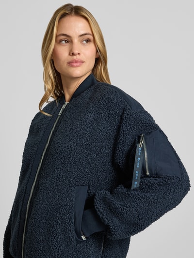 Frauenmodel trägt Teddyjacke mit Stehkragen Modell 'Emeline' von MOS MOSH in Dunkelblau mit Reißverschlusstasche am Ärmel, Nahaufnahme Oberkörper.