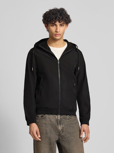 Männermodel trägt zwarte softshell-jack met ritssluiting, ritszakken, capuchon met tunnelkoord van Jack & Jones, regular fit, ganzkörperansicht van voren. Ruglengte maat M 59 cm, schouderbreedte 39 cm, borstwijdte 48 cm, mouwlengte 62 cm.