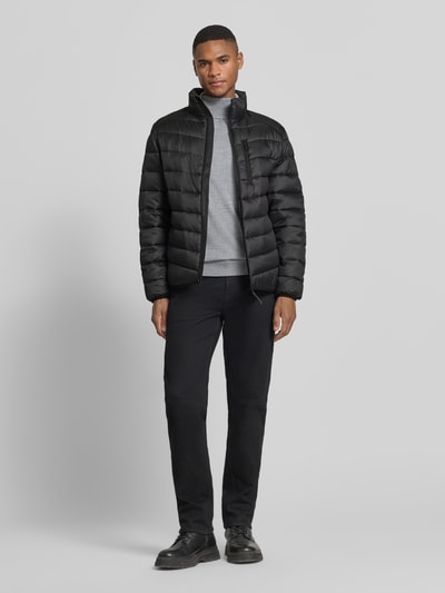 Männermodel trägt Regular Fit gewatteerd jack met verticale ritssluiting borstzak van Tom Tailor Denim, look: effen, opstaande kraag, lange mouw, mouwboord, rompzoom, zij-steekzakken, geheel zwart, glad en gewatteerd oppervlak. Ganzkörperansicht van voren.