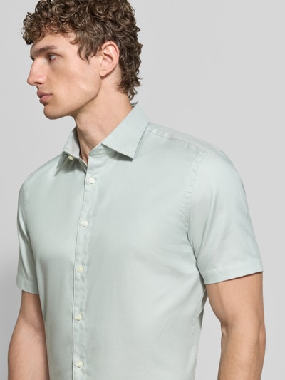 Männermodel trägt Slim Fit Business-Hemd aus Baumwolle mit Kentkragen von Jake*s in hellem Pastellgrün, glatte Textur, Nahaufnahme Oberkörper. Schulterbreite 47 cm, Ärmel 24 cm, Rückenlänge 78 cm bei Größe 39/40.