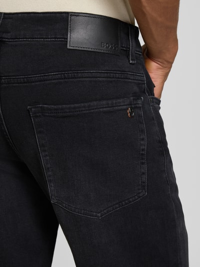 Männermodel trägt Regular Fit Jeansshorts aus Baumwoll-Mix Modell 'RE.MAINE SHORTS BO BORN' von BOSS Orange in dunklem Denim mit Label Patch, Nieten und 5-Pocket-Design, Nahaufnahme Rückansicht.