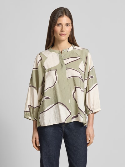 Modelka nosi Bluse mit Rundhalsausschnitt Modell 'Faloom' von OPUS, modal-mix, krój loose fit, z zakrytą listwą guzikową, rękaw 3/4, długość pleców 63 cm, długość rękawa 45 cm, wzór beżowo-oliwkowy z ciemnymi liniami, widok całej sylwetki z przodu.