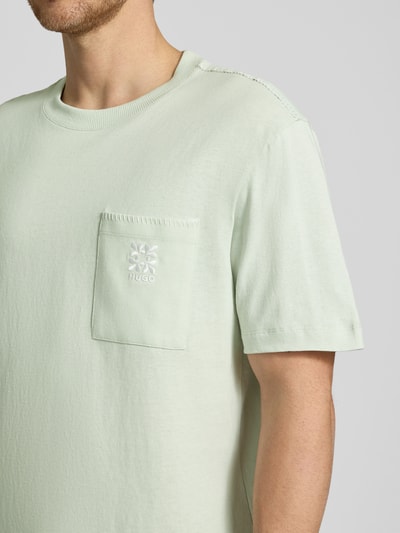 Männermodel trägt Regular Fit T-Shirt aus reiner Baumwolle Modell 'DARRO' von HUGO, Optik: Unifarben, mit Label-Schriftzug, Nahaufnahme Oberkörper.
