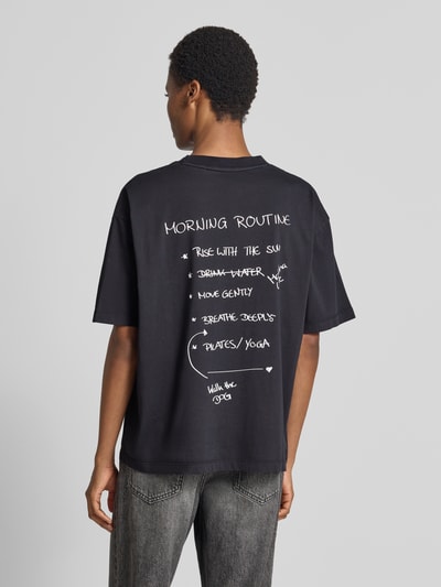 Männermodel trägt czarny t-shirt Regular Fit T-Shirt aus reiner Baumwolle Modell 'C_Eboys_3' von BOSS Orange, tekstura gładka, Ganzkörperansicht Rückansicht.