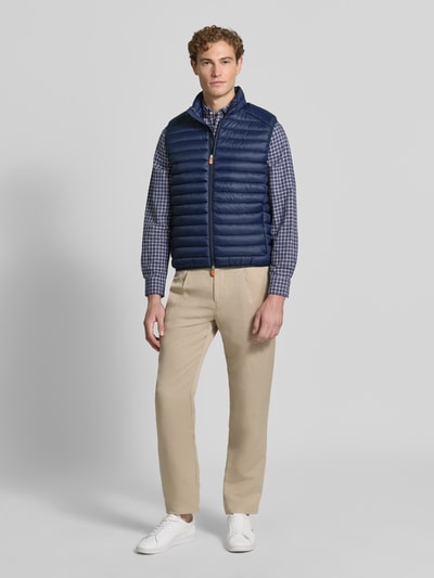 Männermodel trägt Steppweste mit Zweiwege-Reißverschluss Modell 'ADAM' von Save The Duck in Dunkelblau, Regular Fit, Ganzkörperansicht von vorne.