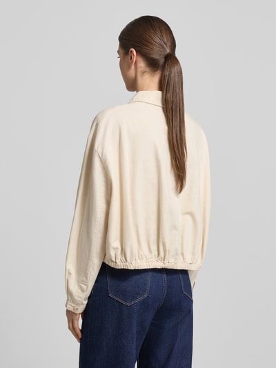 Modelka kobieca nosi Relaxed Fit Hemdjacke aus Baumwoll-Leinen-Mix Modell 'Formente' od OPUS, mieszanka bawełny i lnu, kołnierzyk koszulowy, listwa guzikowa, długość tyłu w rozmiarze 36: 44 cm, długość rękawów w rozmiarze 36: 52 cm, kremowa, widoczna tekstura materiału, widoczne szwy, widoczne marszczenie przy dolnej krawędzi, mocne niebieskie dżinsy, całkowity widok tyłu.