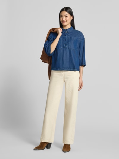 Frauenmodel trägt Relaxed Fit Bluse aus Lyocell-Mix mit Polokragen von Smith and Soul in Denim-Optik, 1/2-Arm, Brusttaschen, blaue Farbe, lockerer Schnitt, kombiniert mit heller Hose und braunen Stiefeletten, Ganzkörperansicht von vorne.