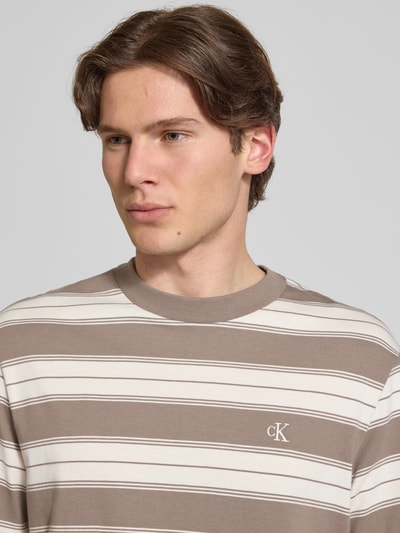 Mannelijk model draagt Regular Fit T-shirt uit katoenmix van Calvin Klein Jeans met all-over gestreept motief, logostitching, ronde hals, korte mouw, close-up bovenlichaam.
