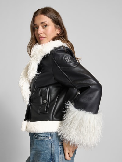 Vrouwenmodel draagt Regular Fit kunstleren jas met dubbele knopenrij model 'SPORTS D' van Marc Cain, zwart-wit, damesjas, zijaanzicht, Nahaufnahme Oberkörper.