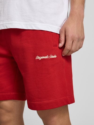Mannenmodel draagt Shorts met Label-Stitching model 'KARL' van Jack & Jones in katoenmix, relaxed fit, rood, details volgens context. Detailopname dij.