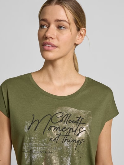 Frauenmodel trägt T-Shirt mit Motiv und Rundhalsausschnitt von Christian Berg Woman, Olivgrün, Regular Fit, Baumwoll-Viskose-Mix, Nahaufnahme Oberkörper.