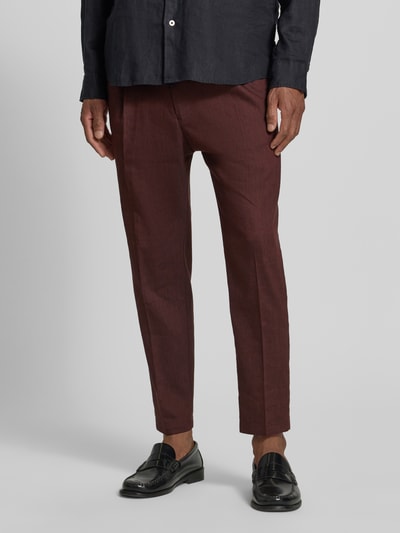Männermodel trägt Hose aus Leinen-Mix mit Gesäßtaschen von Drykorn, bordeaux, schmal geschnitten, Stoffstruktur sichtbar, Nahaufnahme Unterkörper. Slim-Fit, elastischer Bund, Gesäßtaschen, Leinen-Mix mit Viskose-Anteil, Bundweite 40 cm, Innenbeinlänge 66 cm bei Größe 32/32.