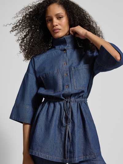 Kobiece model prezentuje Jeansbluse mit Stehkragen und Schnürung von Jake*s Collection, mieszanka bawełny i lnu, taliowany krój, stójka, wiązanie, rękaw o dł. 1/2, głęboki niebieski, tekstura jeansowa. Zbliżenie górnej części ciała z przodu.