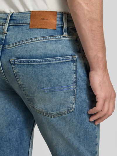 Mężczyzna nosi Regular fit Tapered Jeans aus Baumwoll-Mix Modell 'MAURO' od s.Oliver RED LABEL, jasnoniebieski denim, detal tylnej kieszeni, zbliżenie.