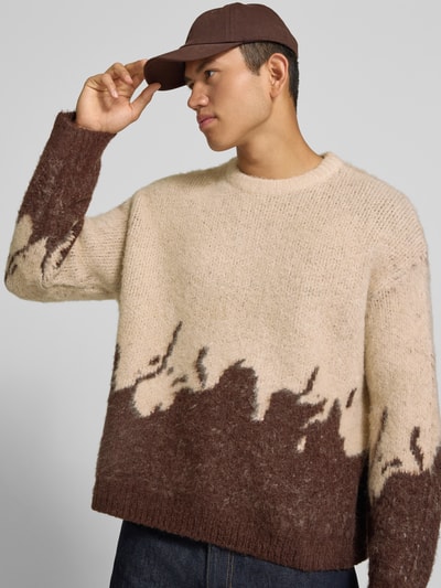 Männermodel trägt Strickpullover mit gerippten Abschlüssen von ANOTHER COTTON LAB, Beige-Braun, lockerer Schnitt, Nahaufnahme Oberkörper. Elastischer Material-Mix mit Lanawoll-Anteil, Rundhalsausschnitt, überschnittene Ärmel, Rückenlänge 62 cm, Ärmellänge 67 cm.