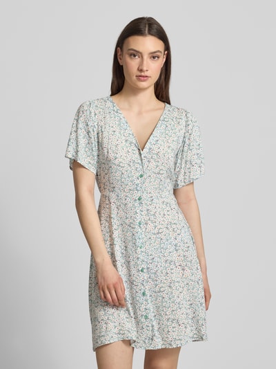 Frauenmodel trägt Minikleid aus reiner Viskose Modell 'EVIDA' von Only mit Allover-Muster, V-Ausschnitt, Knopfleiste, tailliertem Schnitt, Kurzarm und Taillengürtel, Ganzkörperansicht von vorne.