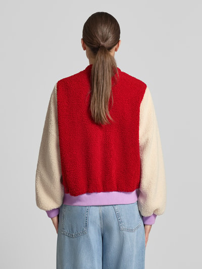 Frauenmodel trägt Fleecejacke mit label-Stickerei Modell 'Lua' von LOLLYS LAUNDRY, rot-cremefarben, lockere Passform, Ganzkörperansicht Rückansicht.