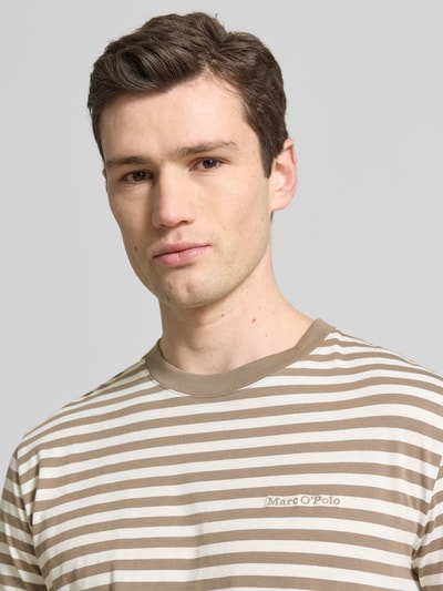 Männermodel trägt Regular Fit T-Shirt aus reiner Baumwolle von Marc O'Polo mit beigem und weißem Allover-Streifenmuster, Nahaufnahme Oberkörper.
