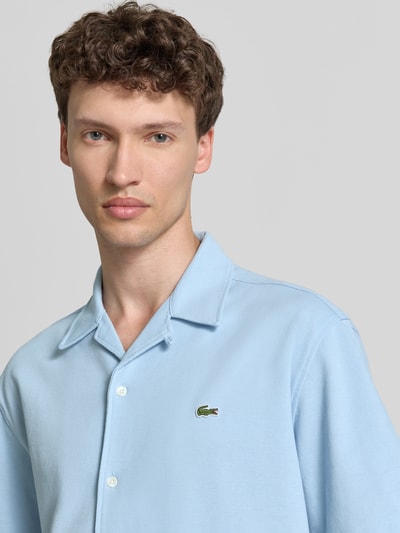 Männermodel trägt Relaxed Fit Freizeithemd aus reiner Baumwolle von Lacoste, Optik: Unifarben, Label-Patch, Nahaufnahme Oberkörper