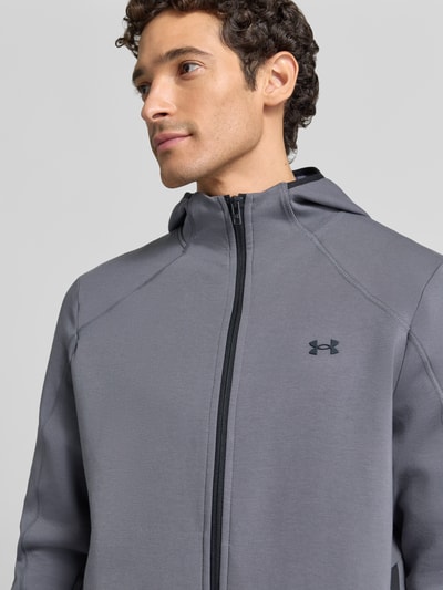 Männermodel trägt Regular Fit Trainingsjacke mit Baumwoll-Anteil Modell 'Unstoppable' von Under Armour in Grau, Nahaufnahme Oberkörper.