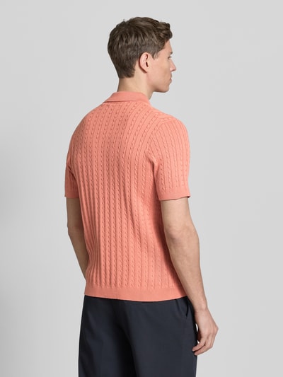 Männermodel trägt Slim Fit Poloshirt in Strick-Optik von Christian Berg Men in Koralle, reine Baumwolle, Rückansicht, Ganzkörperansicht.