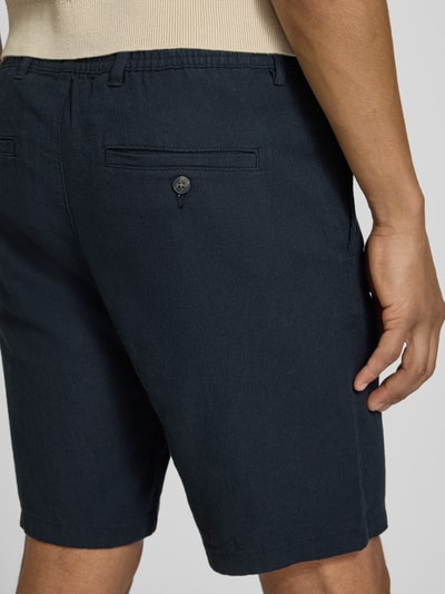 Männermodel trägt Regular Fit Chinoshorts aus Baumwoll-Leinen-Mix Modell 'BRODY' von SELECTED HOMME, dunkelblau, Detailaufnahme Rückansicht.