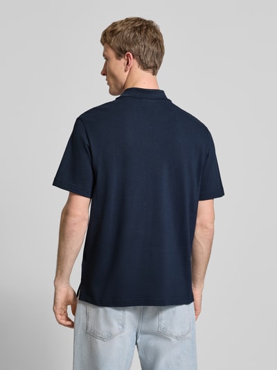 Männermodel trägt Easy Fit Poloshirt mit Polokragen von Calvin Klein Jeans in Dunkelblau aus Reine Baumwolle, Label-Stitching, Ganzkörperansicht Rückansicht. Rückenlänge bei Größe M: 71 cm.