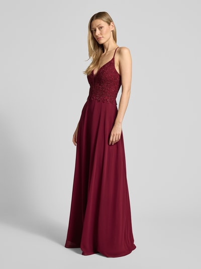 Frauenmodel trägt Regular Fit Abendkleid mit floralem Spitzenbesatz von Luxuar in Dunkelrot mit Spaghettiträgern, taillierter Passform, Ziersteinbesatz und Rückenausschnitt, Stoff wirkt strukturiert und weich, Ganzkörperansicht von vorne.