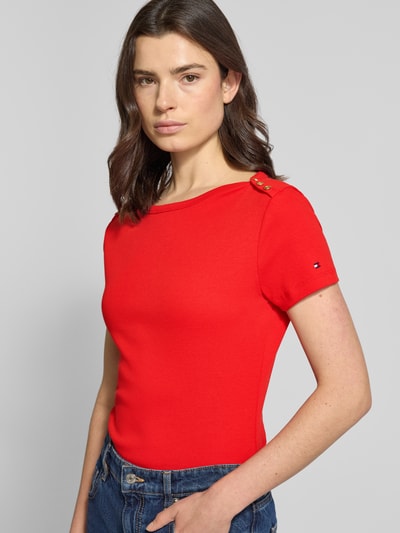 Frauenmodel trägt Slim Fit T-Shirt aus reiner Baumwolle von Tommy Hilfiger in Optik: Unifarben mit Logo-Detail, Zierknöpfe, U-Boot-Ausschnitt, Kurzarm, Materialverarbeitung: Webware, Ganzkörperansicht von vorne.