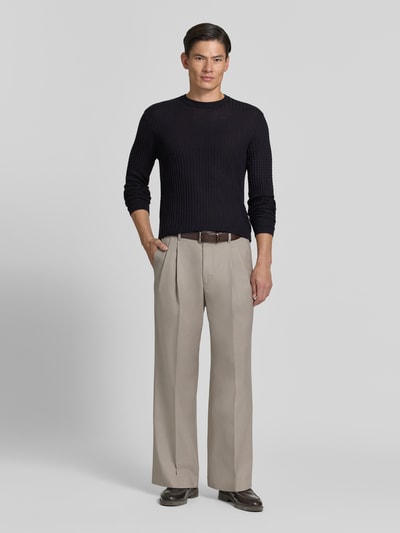 Männermodel trägt Strickpullover mit Struktur-Muster von Emporio Armani in Dunkelblau, taillierter Schnitt, Material-Mix, Ganzkörperansicht von vorne.