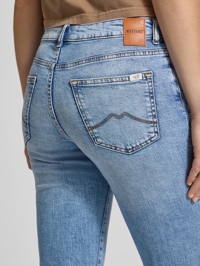 Kobiece modelka nosi jasnoniebieskie Flared Jeans im 5-Pocket-Design model 'Shelby' von Mustang, mieszanka bawełny z dodatkiem streczu, rozkloszowany krój, 5 kieszeni, zapięcie na guzik i zamek błyskawiczny, szerokość w rozmiarze 27/32: 36 cm, długość wewnętrzna nogawki w rozmiarze 27/32: 80 cm, tekstura denimu, detal z tyłu, zbliżenie tylnej części.