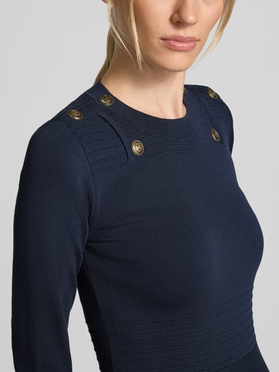 Kobieta nosi sukienkę mini z mieszanki wiskozy, dopasowany krój, ozdobne obszycie, Model 'Abito Maglia' od Liu Jo, zbliżenie na górę ciała.
