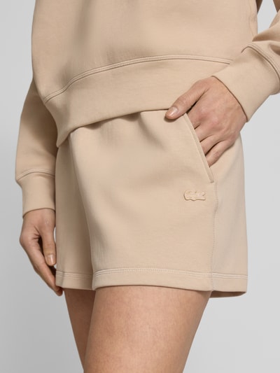 Kobiece modelka nosi Regular Fit Sweatshorts aus Baumwoll-Mix od Lacoste, efekt: jednolity kolor, wyhaftowane logo, tunel, elastyczny ściągacz, wpuszczane kieszenie, kieszeń z tyłu, wykończenie materiału: dzianina dresowa, mieszanka bawełny, zbliżenie na górną część nóg