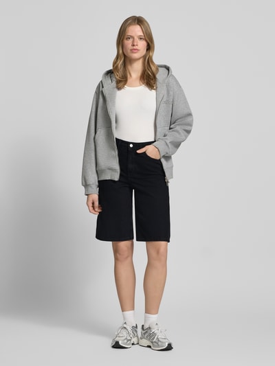 Frauenmodel trägt Long Shorts im 5-Pocket-Design Modell 'TOKYO' von JJXX in Schwarz, reine Baumwolle, Wide Fit, Ganzkörperansicht von vorne.