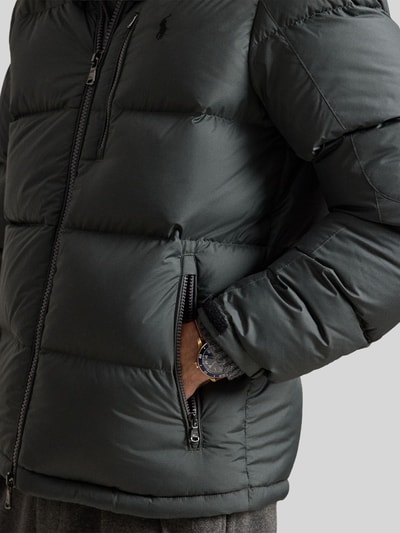 Männermodel trägt Regular Fit Daunenjacke mit Logo-Stitching von Polo Ralph Lauren in Dunkelgrau mit mattem Finish, Nahaufnahme Oberkörper. Herren Daunenjacke von Polo Ralph Lauren.